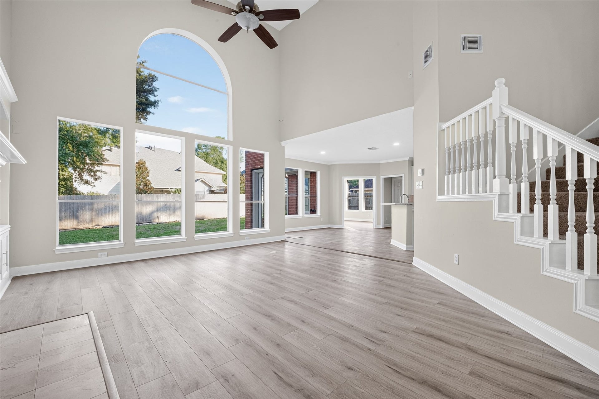 3610 Forest Row Drive, Houston, TX 77345 Soaring ceilings and a dramatic arched window bring abundant natural light into the living room. Wood-look flooring, backyard views, and an open connection to the breakfast area create an inviting gathering space.