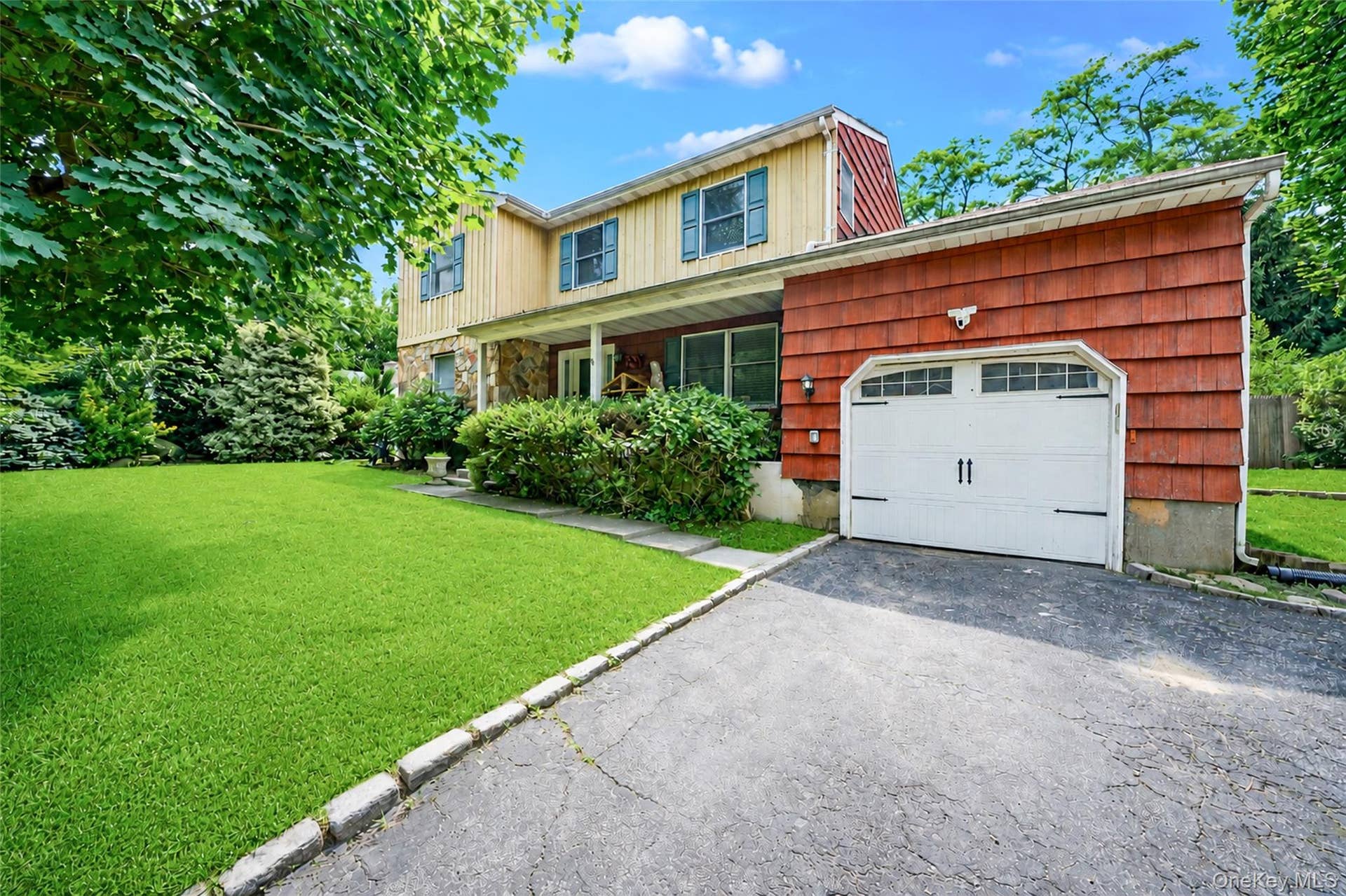 2 Berkeley Place, Sea Cliff, NY 11579 Exterior featuring a stone facade, red shingle siding, and a white garage door with decorative hardware