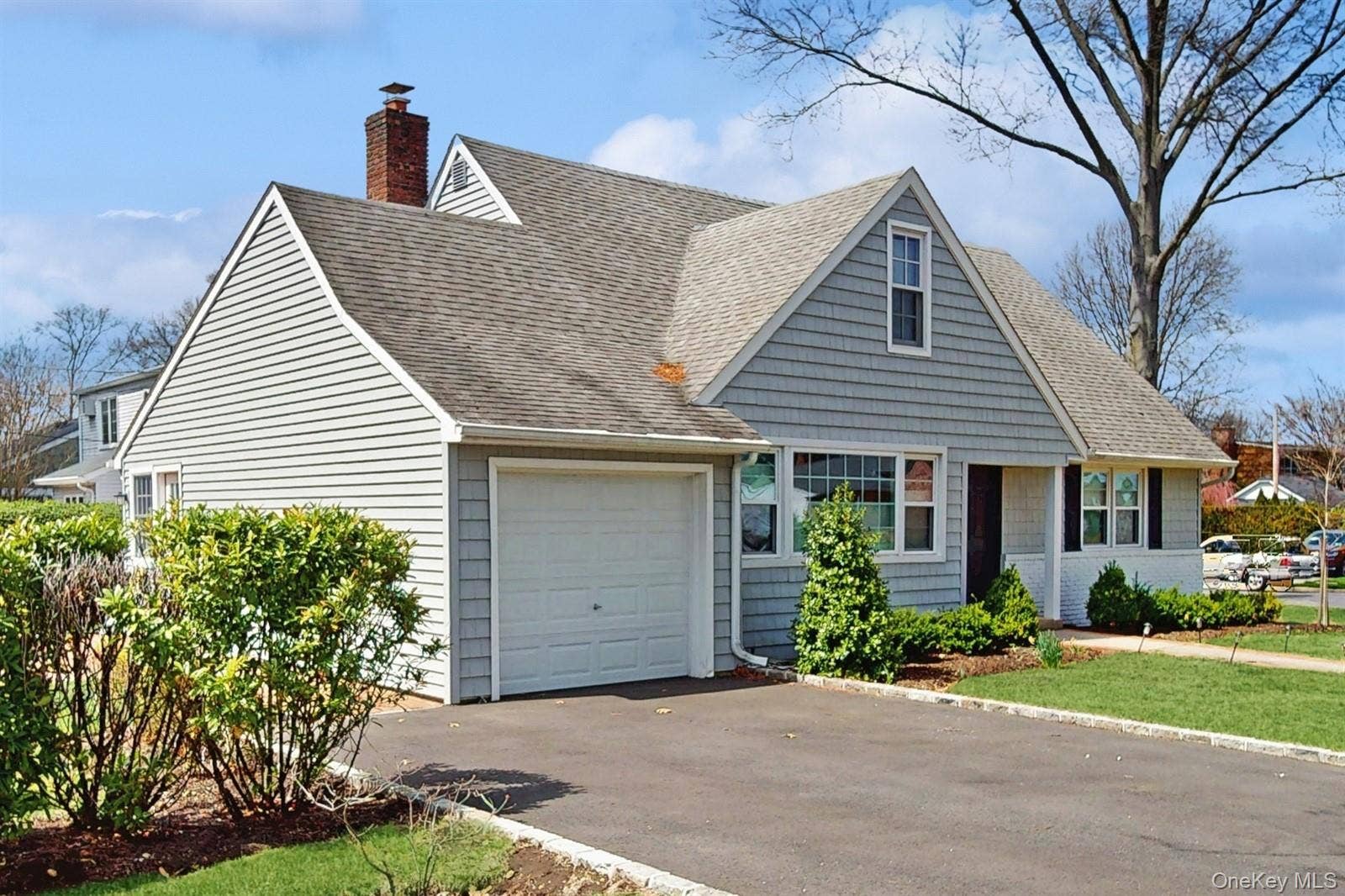 170 Wetherill Road, Garden City, NY 11530 New england style home with a garage, driveway, a chimney, and a shingled roof