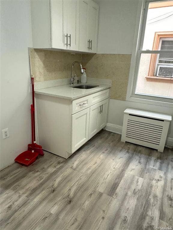 3138 103rd Street, #2ND FL, Corona, NY 11368 White shaker cabinetry, light-toned backsplash, stainless steel sink with a gooseneck faucet, light-toned countertop, and wood-finish flooring