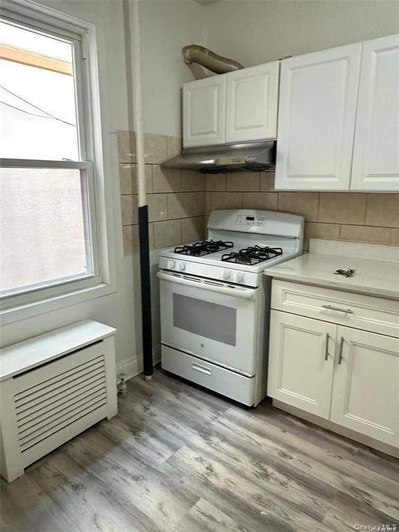 3138 103rd Street, #2ND FL, Corona, NY 11368 White shaker-style cabinetry, stainless steel range hood, tile backsplash, wood-finish flooring, and a white gas range