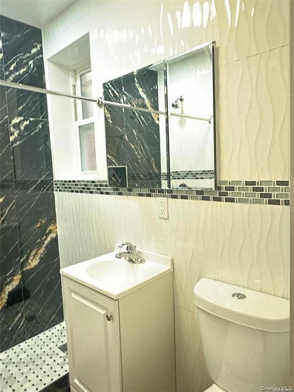 3138 103rd Street, #2ND FL, Corona, NY 11368 Shower with black and gold-veined tile, mosaic accent border, white wave-patterned wall tile, and a white vanity with an integrated sink