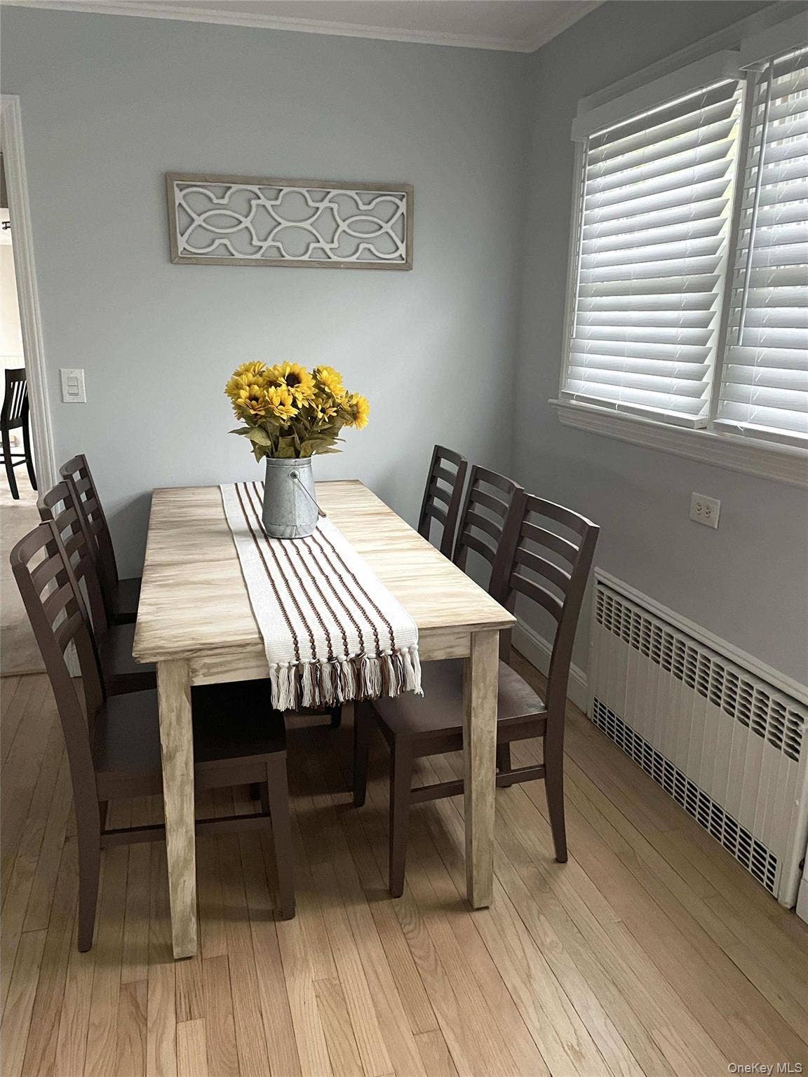 Dining area with radiator, crown molding, and light wood-style flooring