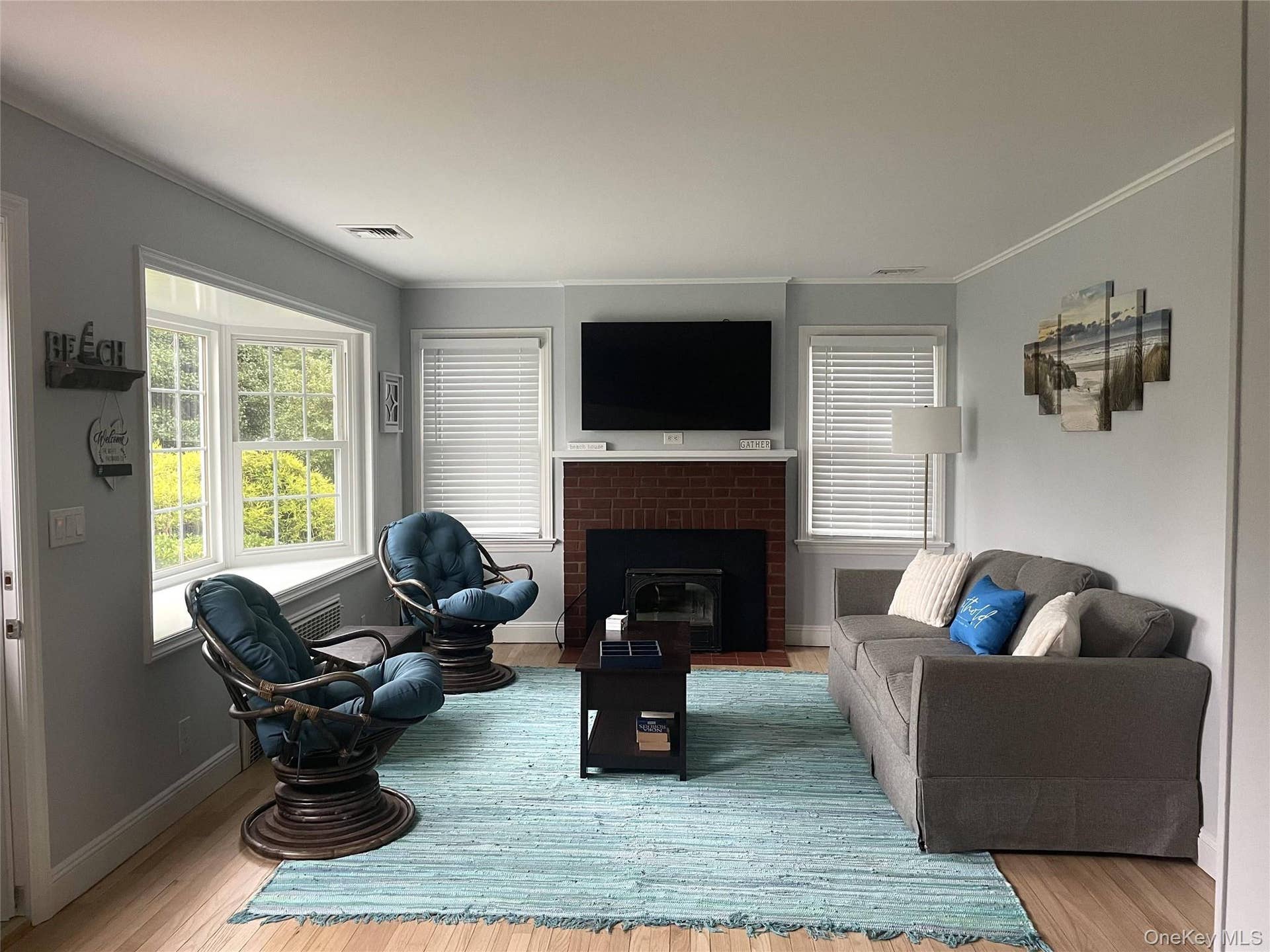 Living room featuring a fireplace, healthy amount of natural light, crown molding, and wood finished floors