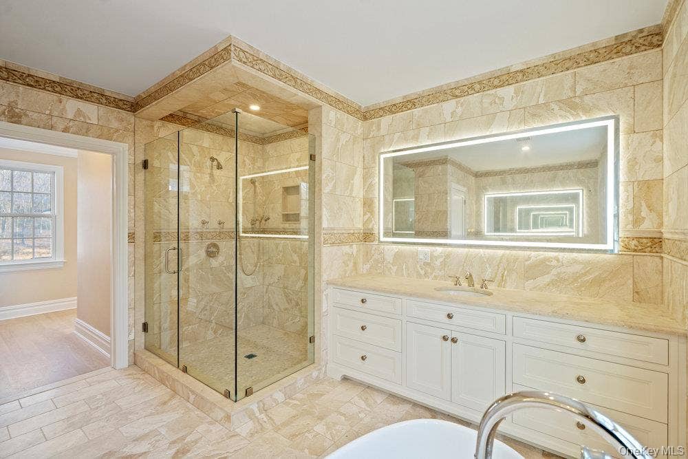 89 Mill River Road, Upper Brookville, NY 11771 Bathroom with vanity, tile walls, a shower stall, light marble finish floors, and a soaking tub