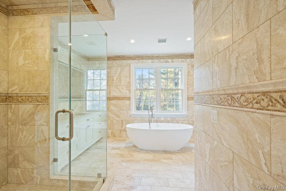 89 Mill River Road, Upper Brookville, NY 11771 Bathroom featuring a freestanding bath, a shower stall, tile walls, and recessed lighting