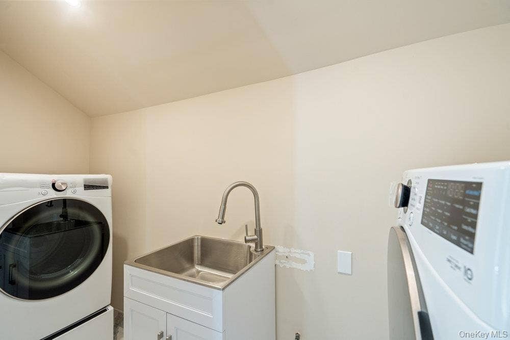 89 Mill River Road, Upper Brookville, NY 11771 Washroom featuring washer / clothes dryer, lofted ceiling, and cabinet space