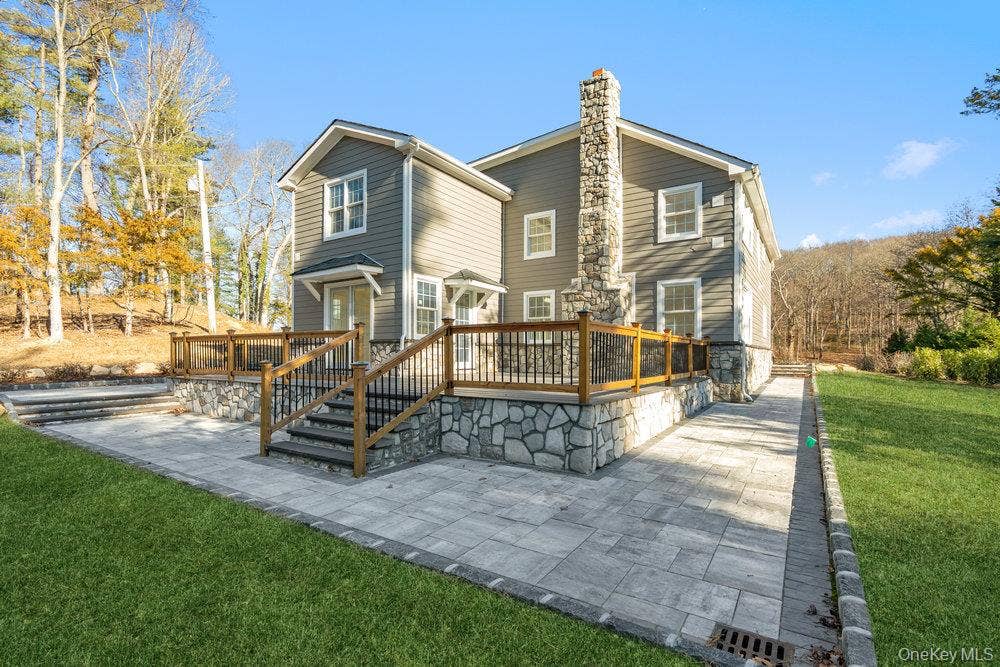 89 Mill River Road, Upper Brookville, NY 11771 Rear view of property with a yard, a wooden deck, a patio, and a chimney