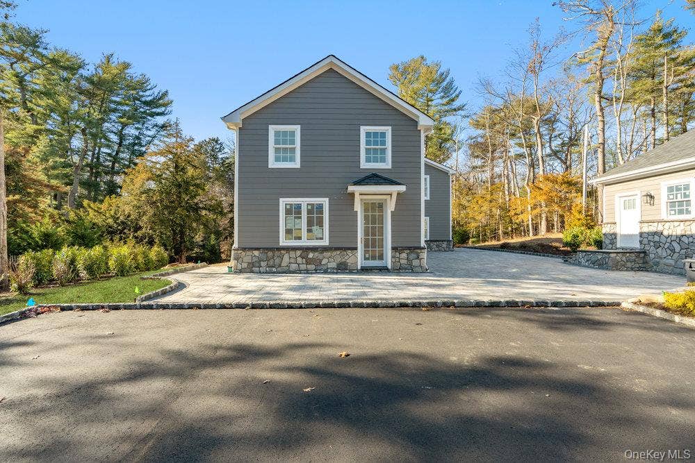 89 Mill River Road, Upper Brookville, NY 11771 Rear view of property featuring a patio and stone siding
