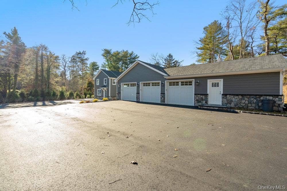 89 Mill River Road, Upper Brookville, NY 11771 View of side of home featuring stone siding and driveway