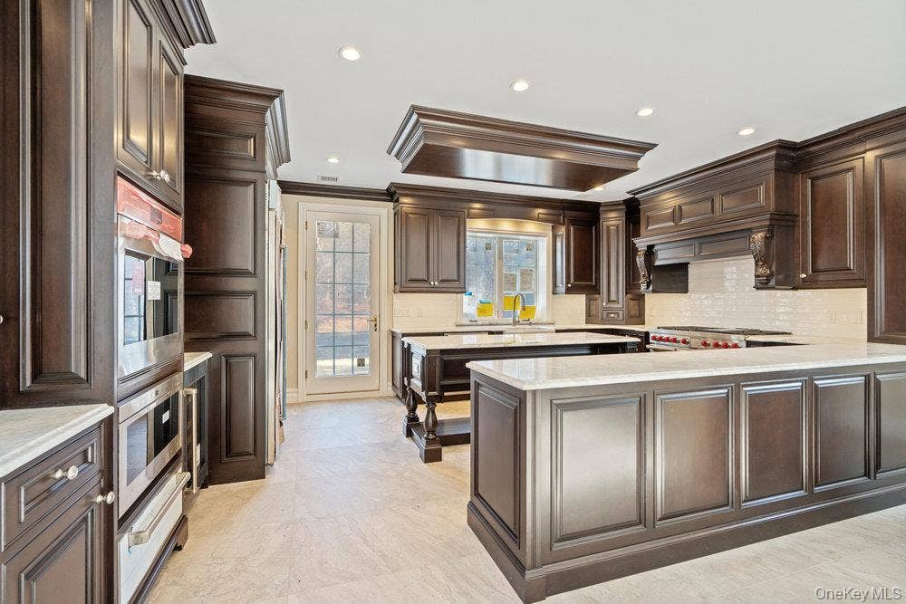 89 Mill River Road, Upper Brookville, NY 11771 Kitchen with dark brown cabinets, a peninsula, tasteful backsplash, crown molding, and recessed lighting