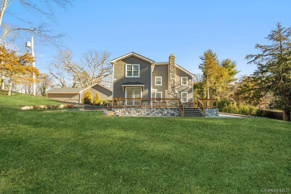 89 Mill River Road, Upper Brookville, NY 11771 Back of property with a lawn, a chimney, and a deck