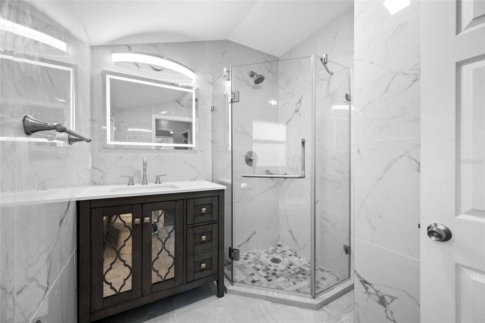 5044 BETTY STREET N, St Petersburg, FL 33709 Primary Bedroom suite with walk-in closet, with built in shevles, that opens through to private en-suite updated bathroom with marble tile and glass shower.
