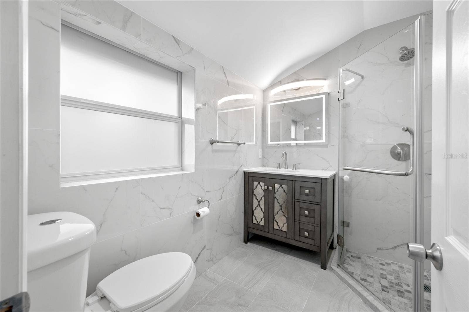 5044 BETTY STREET N, St Petersburg, FL 33709 Primary Bedroom suite with walk-in closet, with built in shevles, that opens through to private en-suite updated bathroom with marble tile and glass shower.