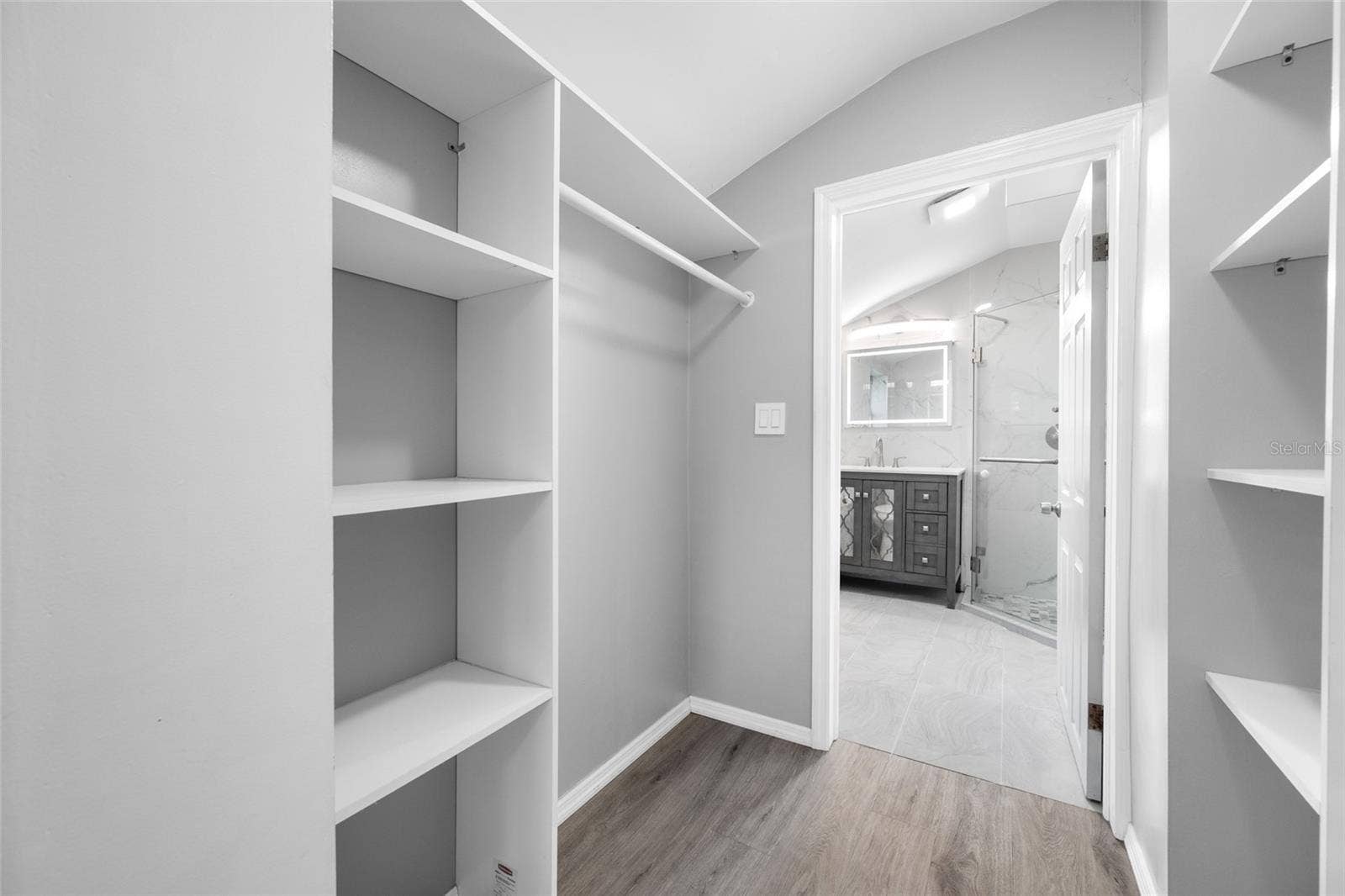 5044 BETTY STREET N, St Petersburg, FL 33709 Primary Bedroom suite with walk-in closet, with built in shevles, that opens through to private en-suite updated bathroom with marble tile and glass shower.