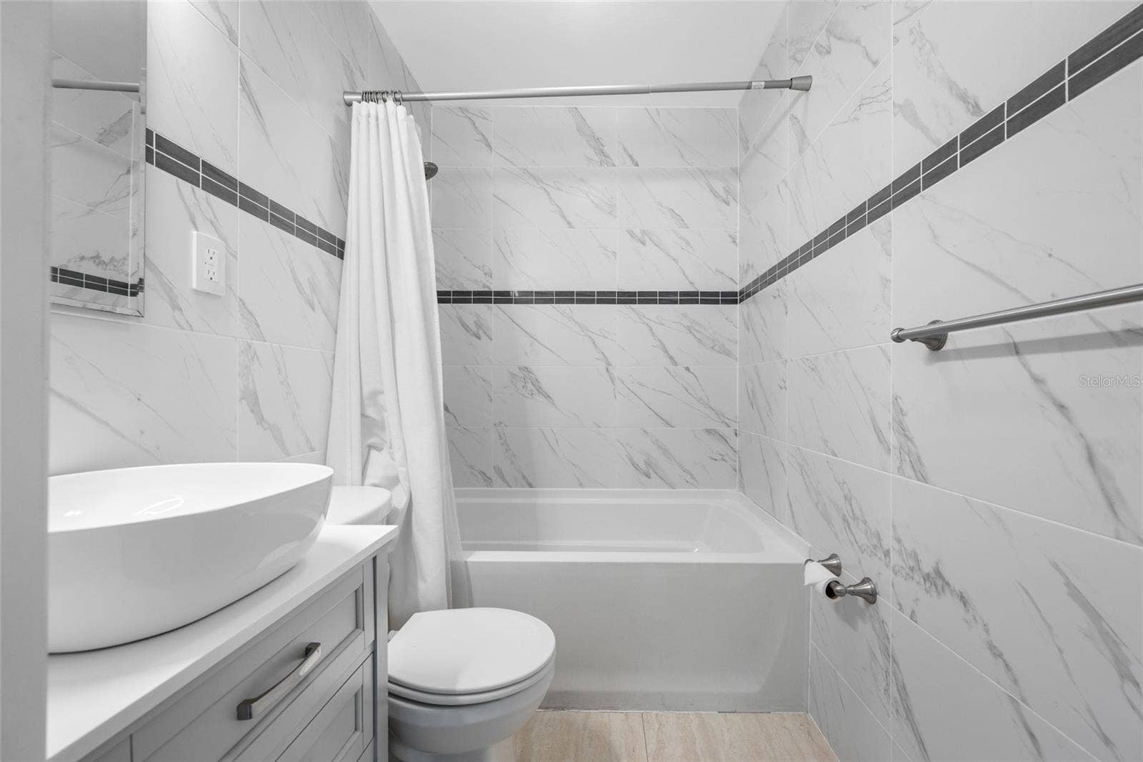 5044 BETTY STREET N, St Petersburg, FL 33709 Bathroom 2 features an upgraded vanity, marble tiles, and a bathtub with shower.