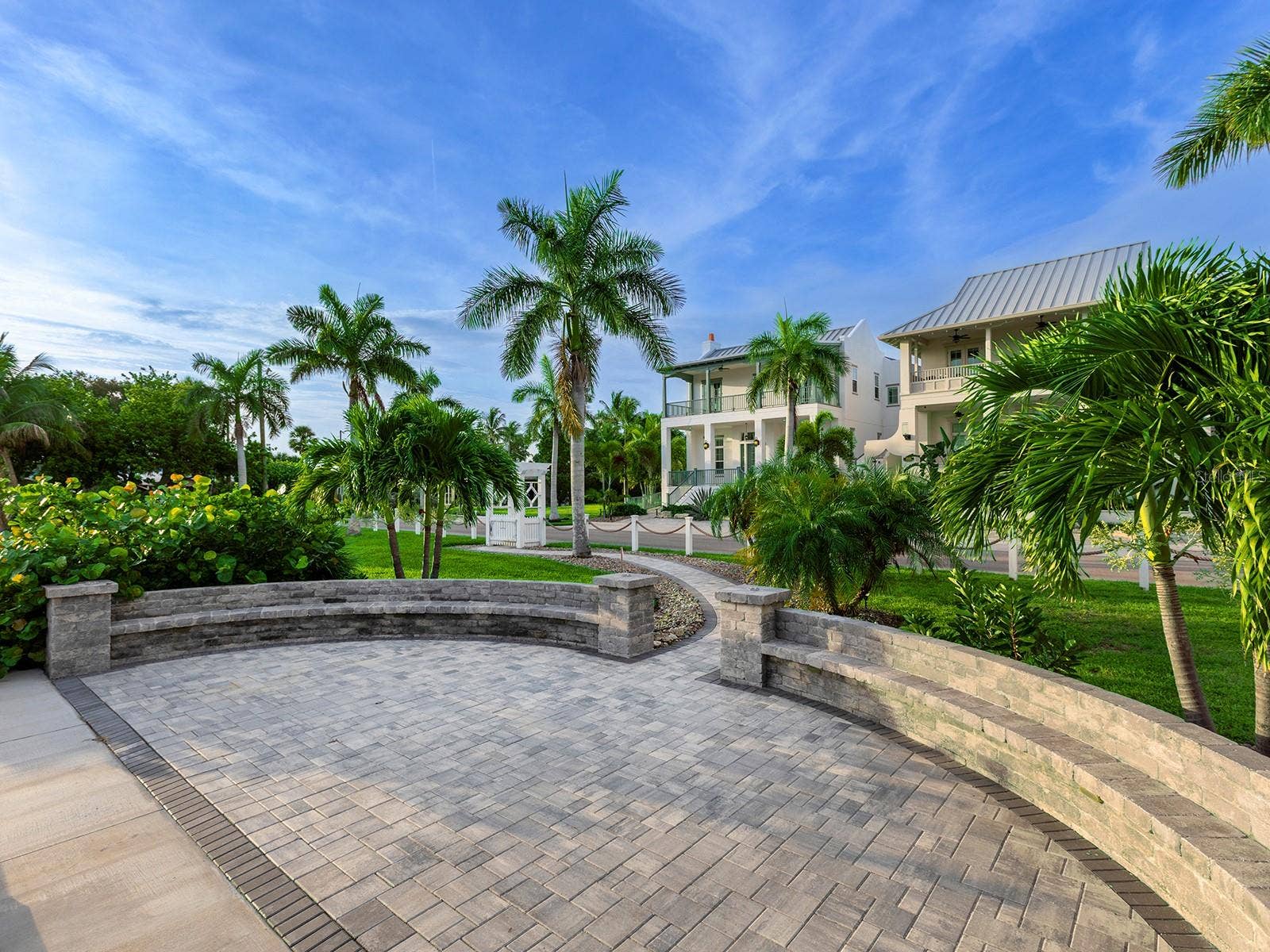 4024 11TH STREET COURT W, Palmetto, FL 34221 Serene waterfront patio space with custom paver stones and curved stone seating, nestled among lush tropical landscaping beside your dock