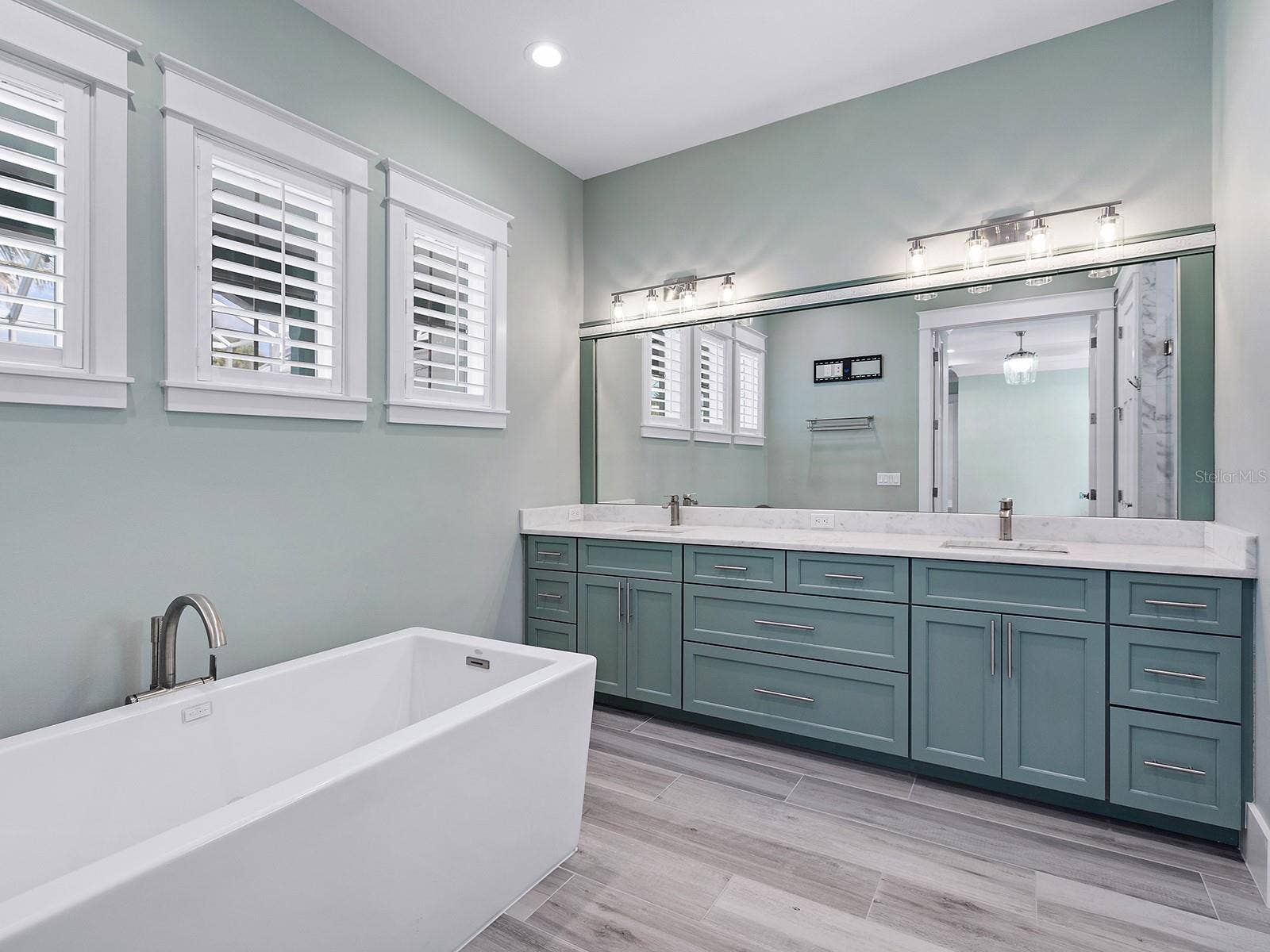 4024 11TH STREET COURT W, Palmetto, FL 34221 Main-level primary bath featuring a freestanding soaking tub, shaker vanity, and plantation shutters
