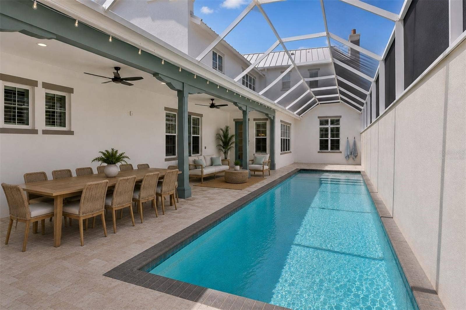 4024 11TH STREET COURT W, Palmetto, FL 34221 Virtually staged approximately 70-foot pool deck featuring covered outdoor dining, a lounge area, tanning space, and direct access to the main-level primary suite