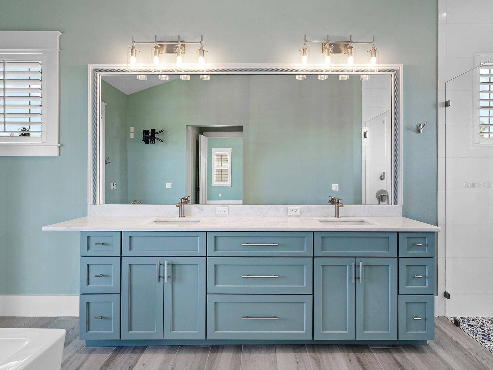4024 11TH STREET COURT W, Palmetto, FL 34221 Spanning double vanity featuring elegant light teal cabinetry, a massive full-width mirror with dual vanities, and white quartz countertops