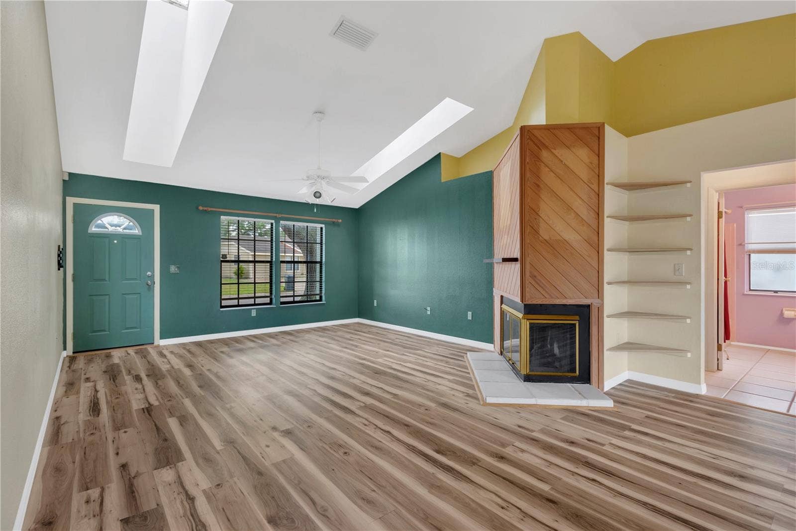 5546 34TH COURT E, Bradenton, FL 34203 Living Room with wood burning fireplace and built in corner shelves.