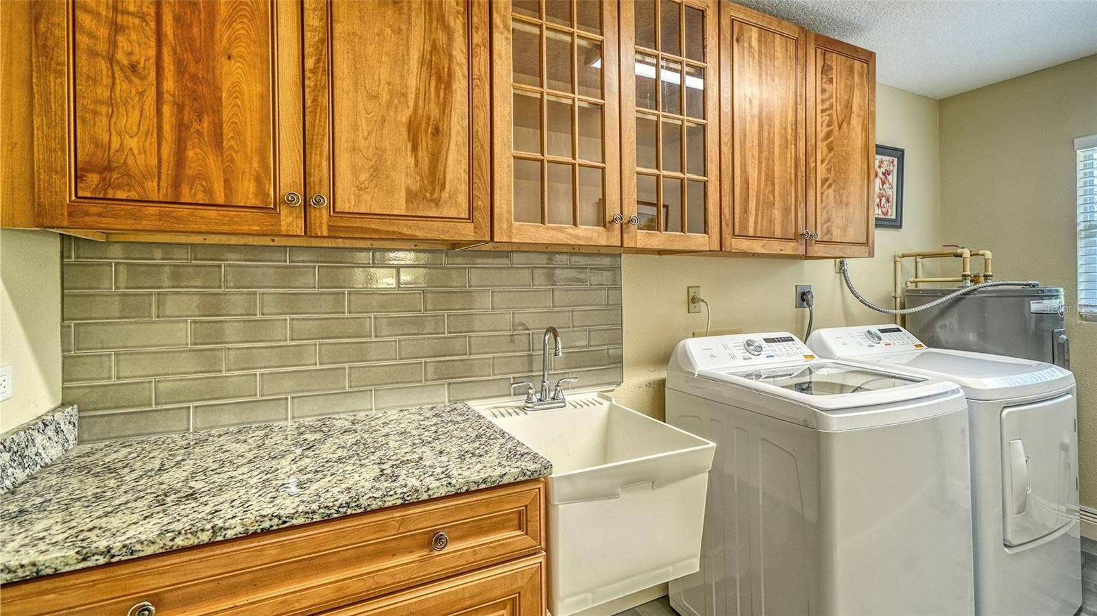 Convenient laundry room with cabinetry and new washer and dryer.