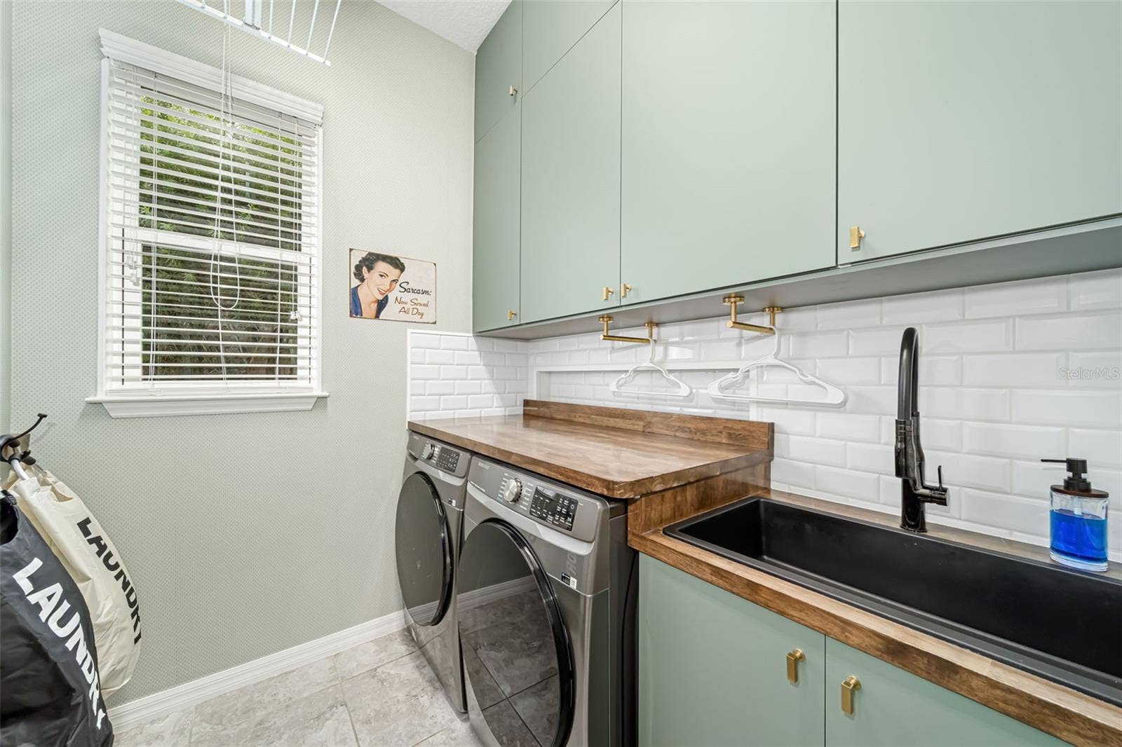 Thoughtfully designed laundry room with a utility sink and custom folding racks.