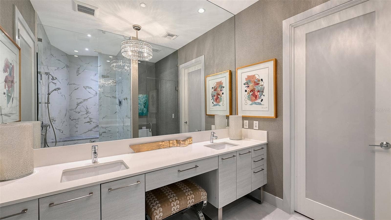 1155 N GULFSTREAM AVENUE, #207, Sarasota, FL 34236 An elegant primary bath featuring dual sinks, a dedicated makeup vanity with an oversized mirror, and a custom chandelier for a touch of refined luxury.