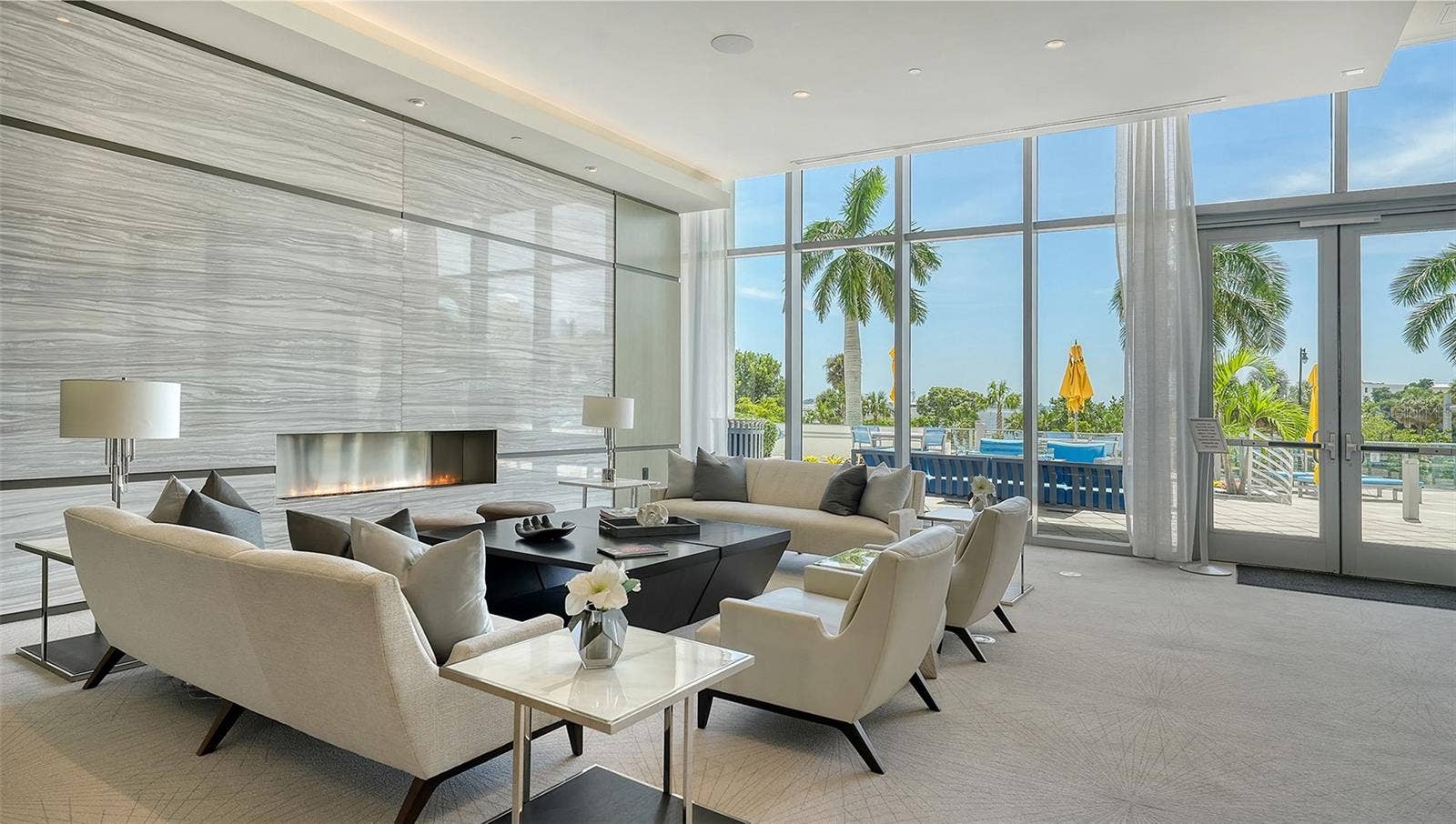 1155 N GULFSTREAM AVENUE, #207, Sarasota, FL 34236 An expansive luxury lobby lounge featuring elegant seating and a welcoming fireplace, creating a sophisticated setting for relaxation and gathering with guests.