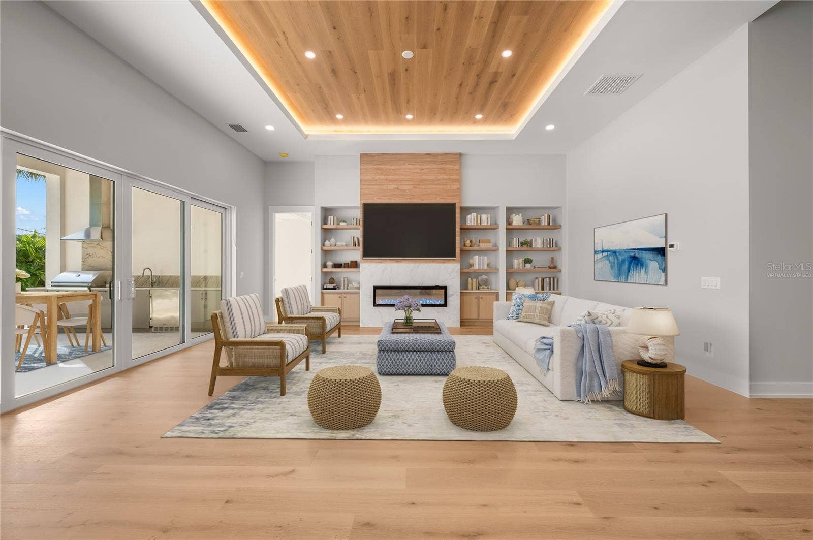 3360 BAYOU SOUND, Longboat Key, FL 34228 Virtually staged family room featuring a modern fireplace and custom built-ins, opening seamlessly to the outdoor entertaining area.