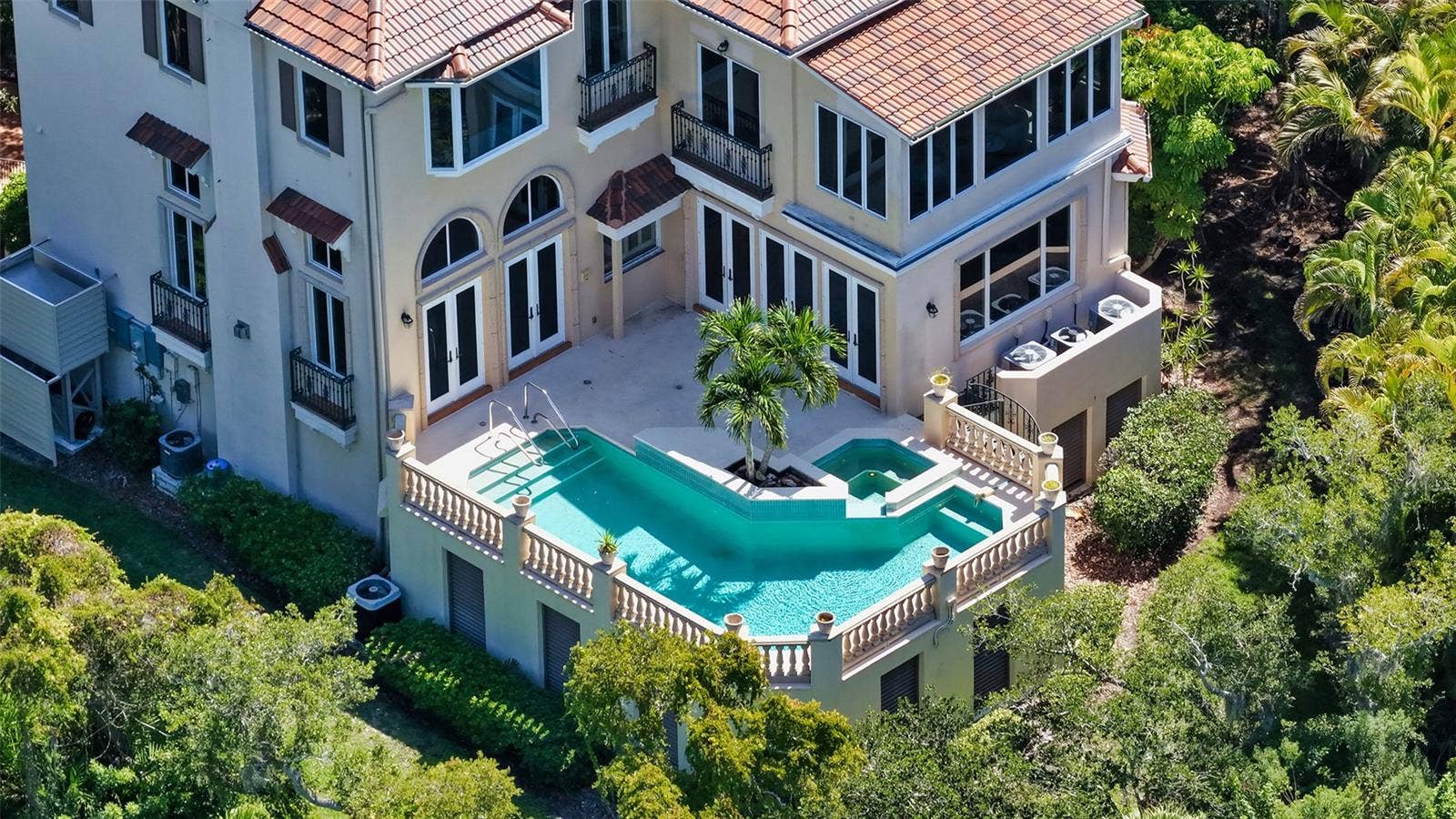 168 COASTAL HAMMOCK COURT, Osprey, FL 34229 An aerial view highlights the home's elevated pool and spa tucked into the lush surrounding landscape.