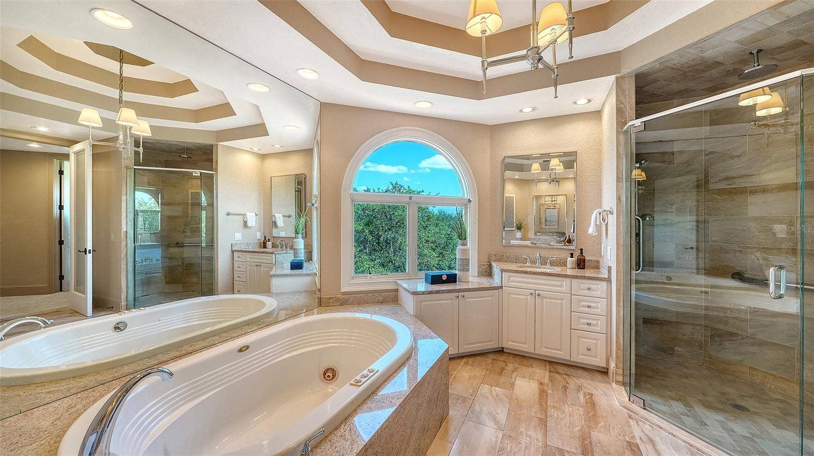 168 COASTAL HAMMOCK COURT, Osprey, FL 34229 A spacious glass enclosed shower and soaking tub complement the beautifully appointed primary suite.