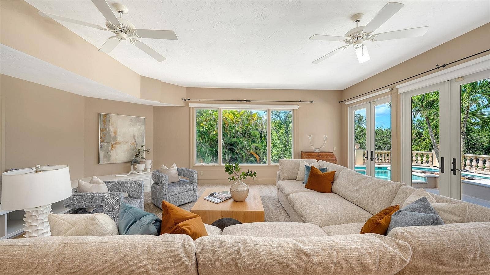 168 COASTAL HAMMOCK COURT, Osprey, FL 34229 Expansive windows and French doors surround this comfortable gathering space with views of the lush tropical setting.