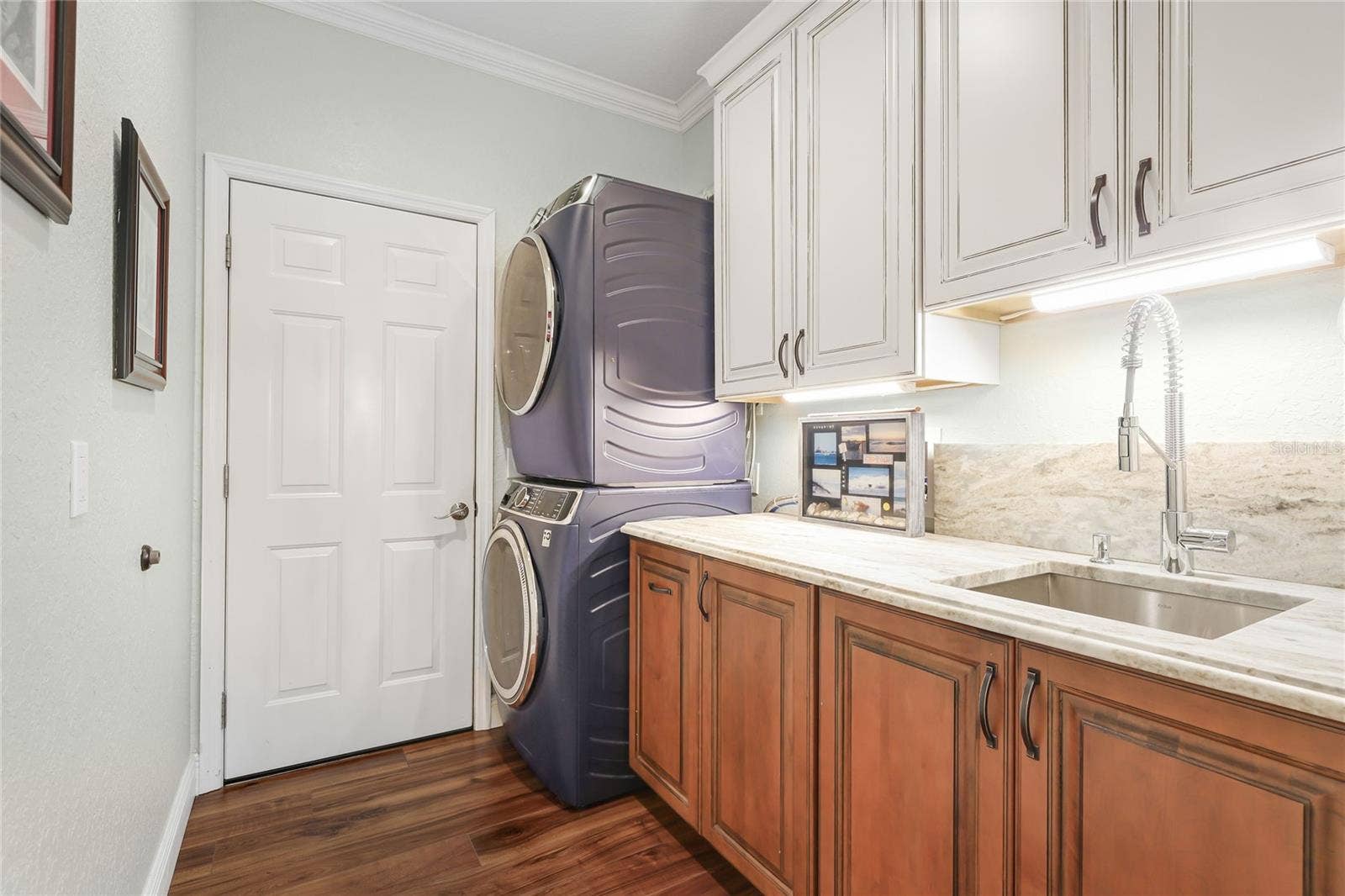3306 LITTLE COUNTRY ROAD, Parrish, FL 34219 New laundry room featuring custom cabinetry, granite counter with backsplash, and stacked GE profile washer & dryer.