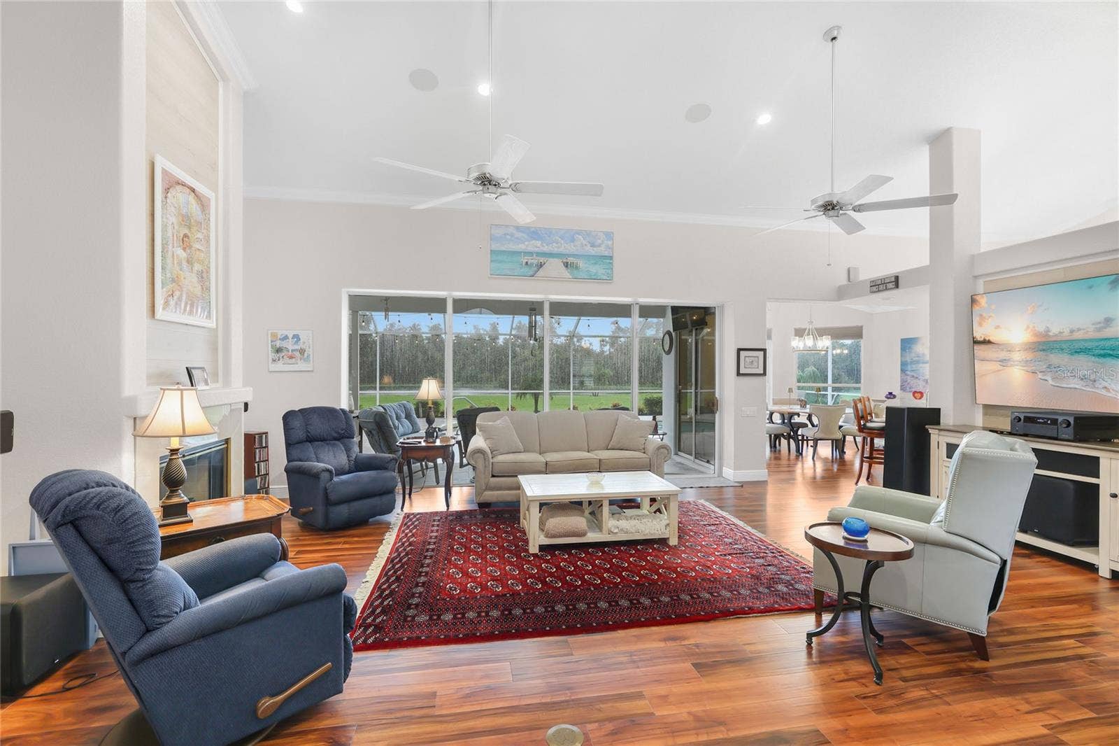 3306 LITTLE COUNTRY ROAD, Parrish, FL 34219 The great room has high ceilings, luxury vinyl plank flooring, six-inch crown molding, ceiling fans, and a poolside lake view