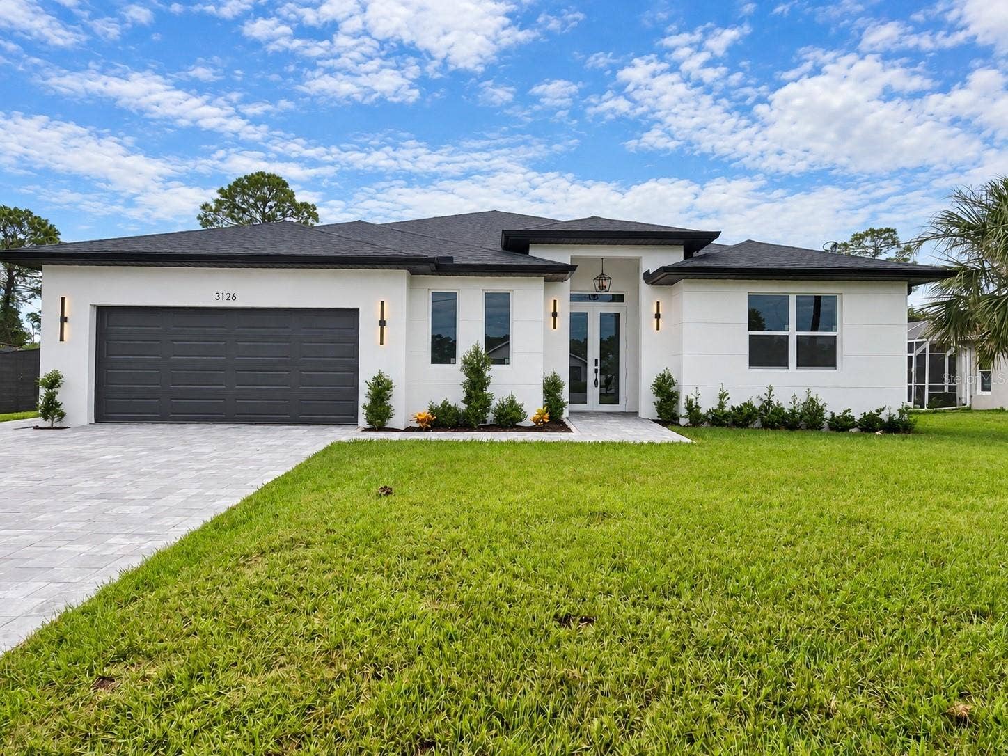 3126 BELLEVILLE TER, North Port, FL 34286 Front exterior with modern design, a two-car garage, and spacious driveway.