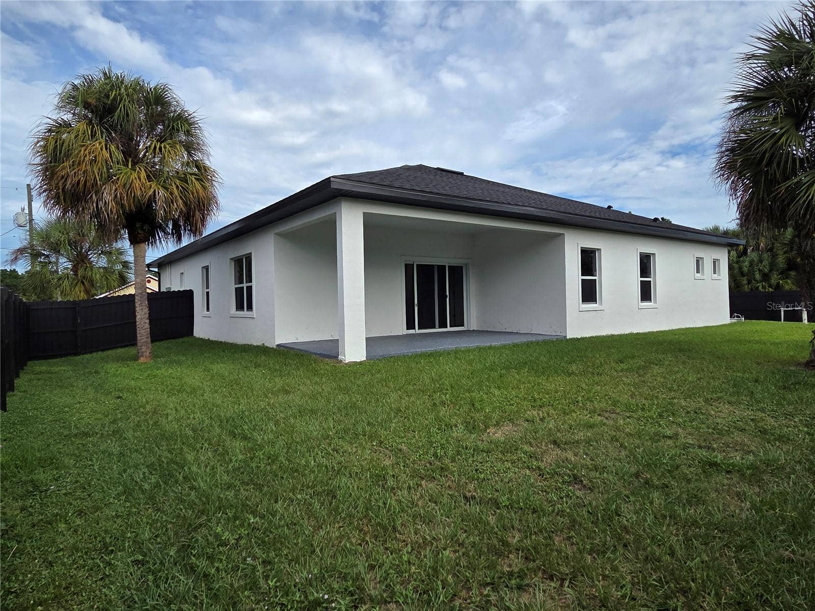 3126 BELLEVILLE TER, North Port, FL 34286 Rear exterior showcasing the covered patio and expansive lawn.