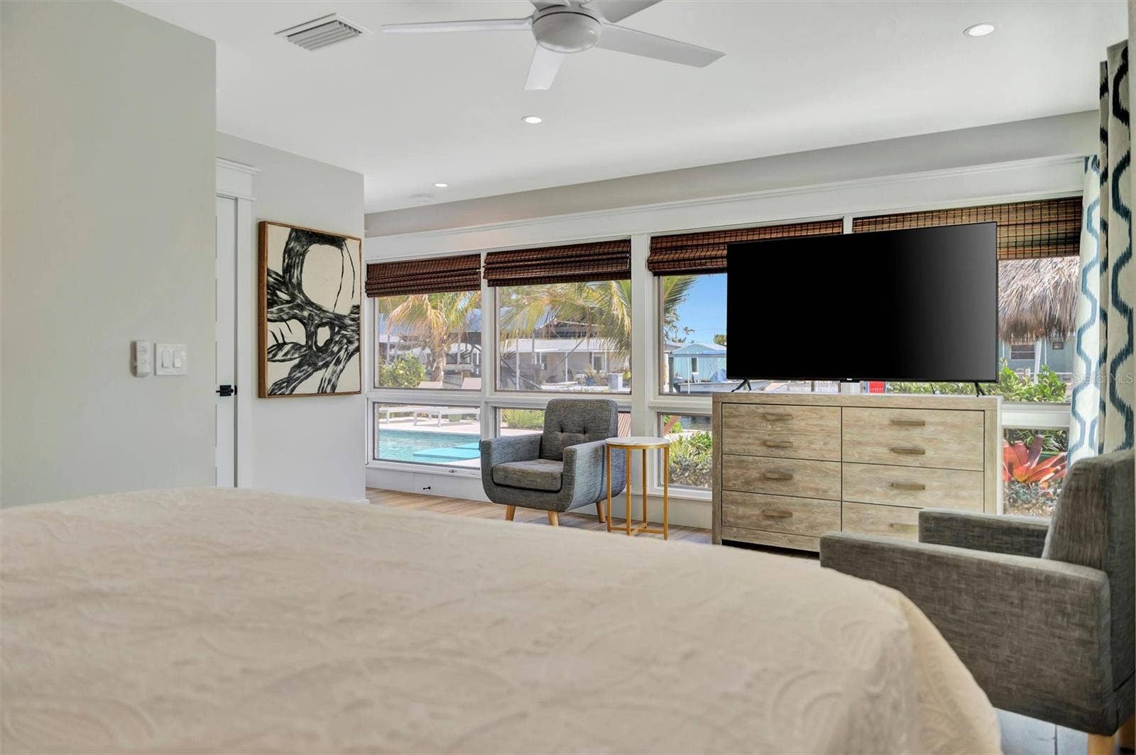 10115 KINGFISHER ROAD E, Bradenton, FL 34209 Primary suite with sliding glass doors, gorgeous views of the pool, turf area, and canal, plus an ensuite bathroom.