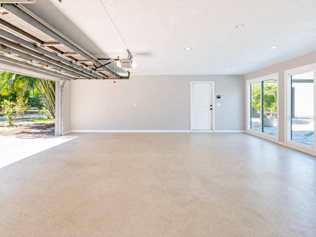 403 LONGBOW TRAIL, Osprey, FL 34229 Expansive three-car garage offering exceptional space, with multiple glass doors providing natural light and convenient access toward the pool area