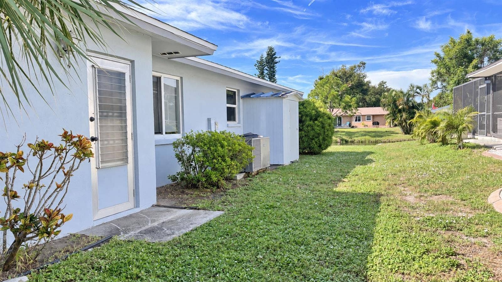 160 ANNAPOLIS LANE, Rotonda West, FL 33947 Side of home with doorway to garage, water side views, and storage shed.