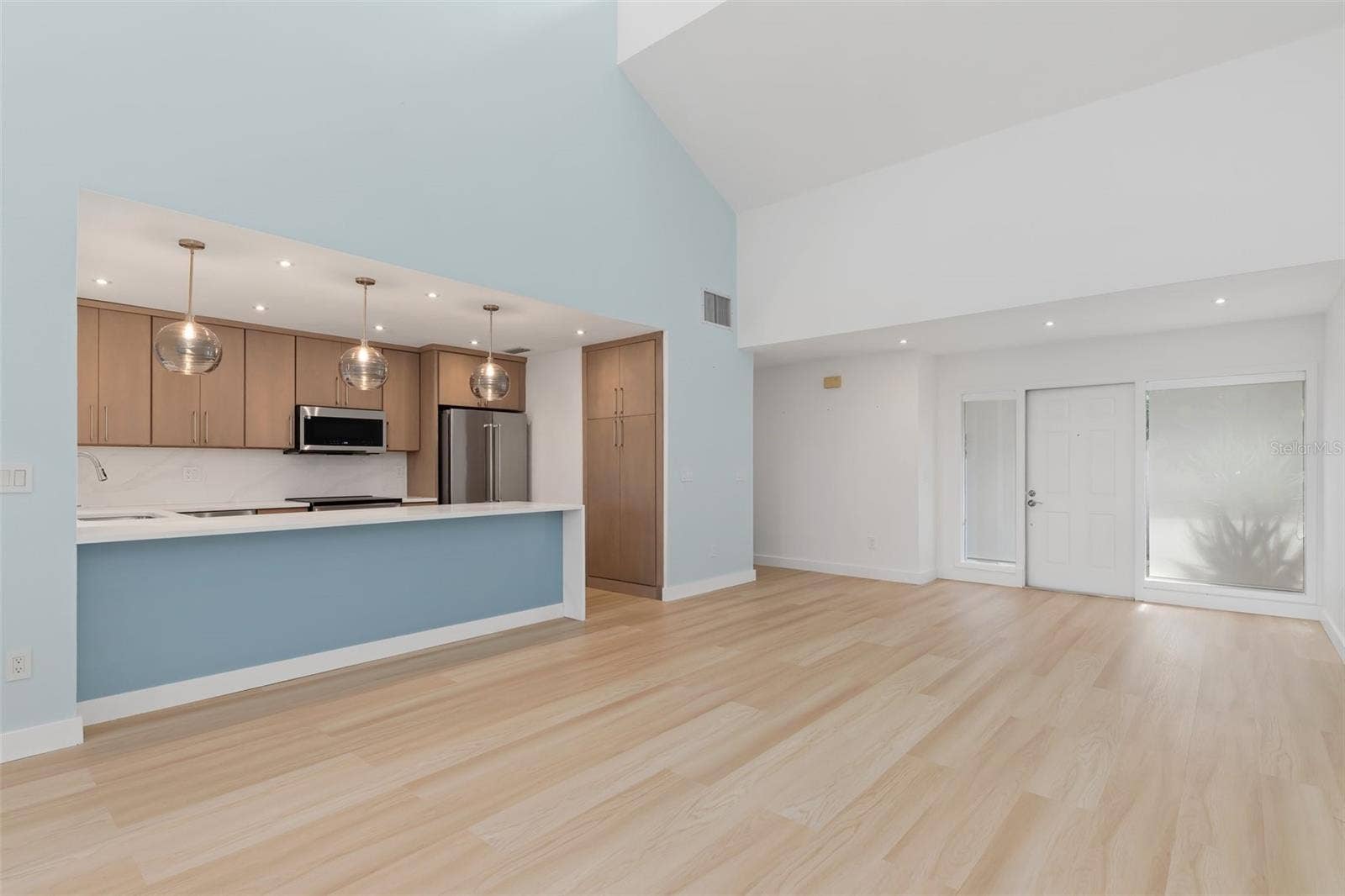 5021 SAN ROCCO COURT, Punta Gorda, FL 33950 Great room unfurnished. Kitchen breakfast bar with lighted blue glass face, modern cabinetry and pendant lighting.