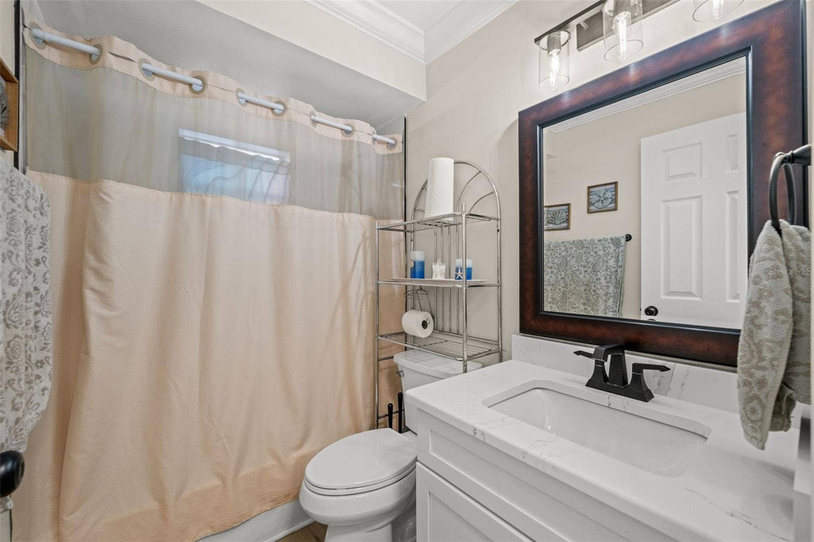 A bathroom featuring a quartz countertop, fresh paint, and a tub - shower combo.