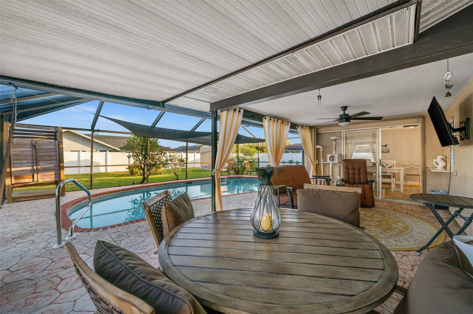 The screened-in lanai offers an attractive stone-pattern floor, a decorative lighted ceiling fan, and easy access to your heated pool. Notice the outdoor shower?