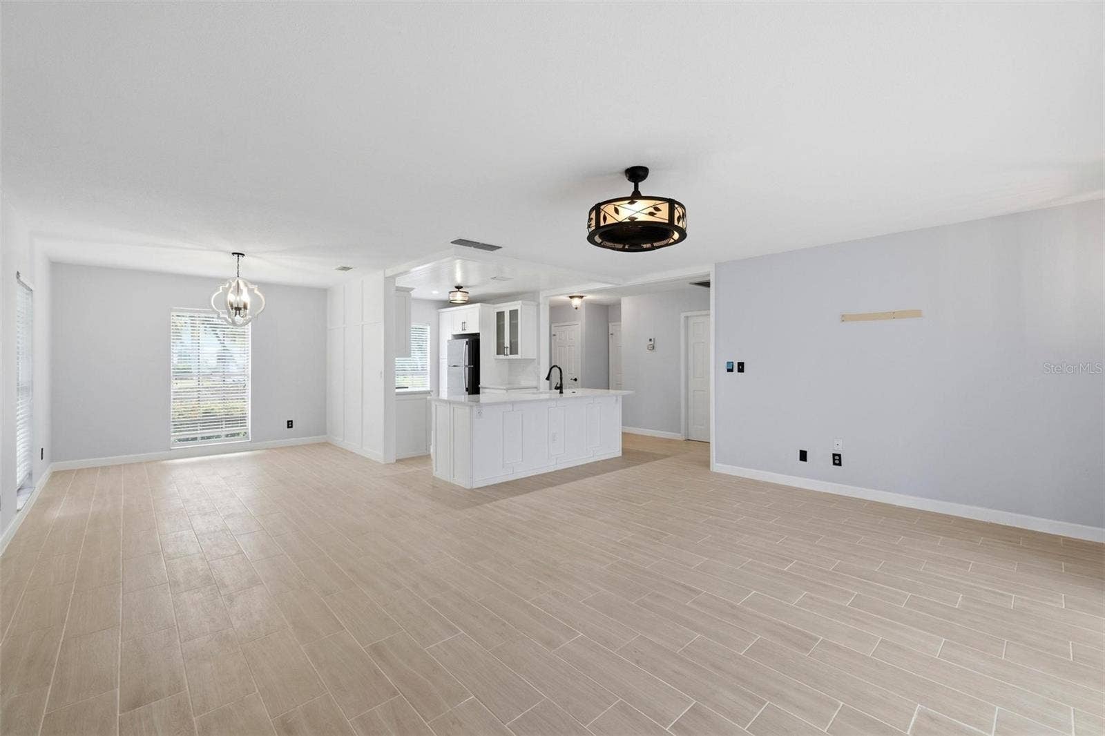 This view shows the open floorplan including living room, dining room and kitchen including a view of the newly laid tile floors throughout the home.