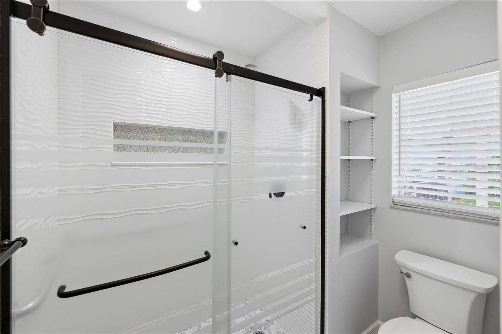 Another view of the primary bath shower and toilet area along with window for light and bright!