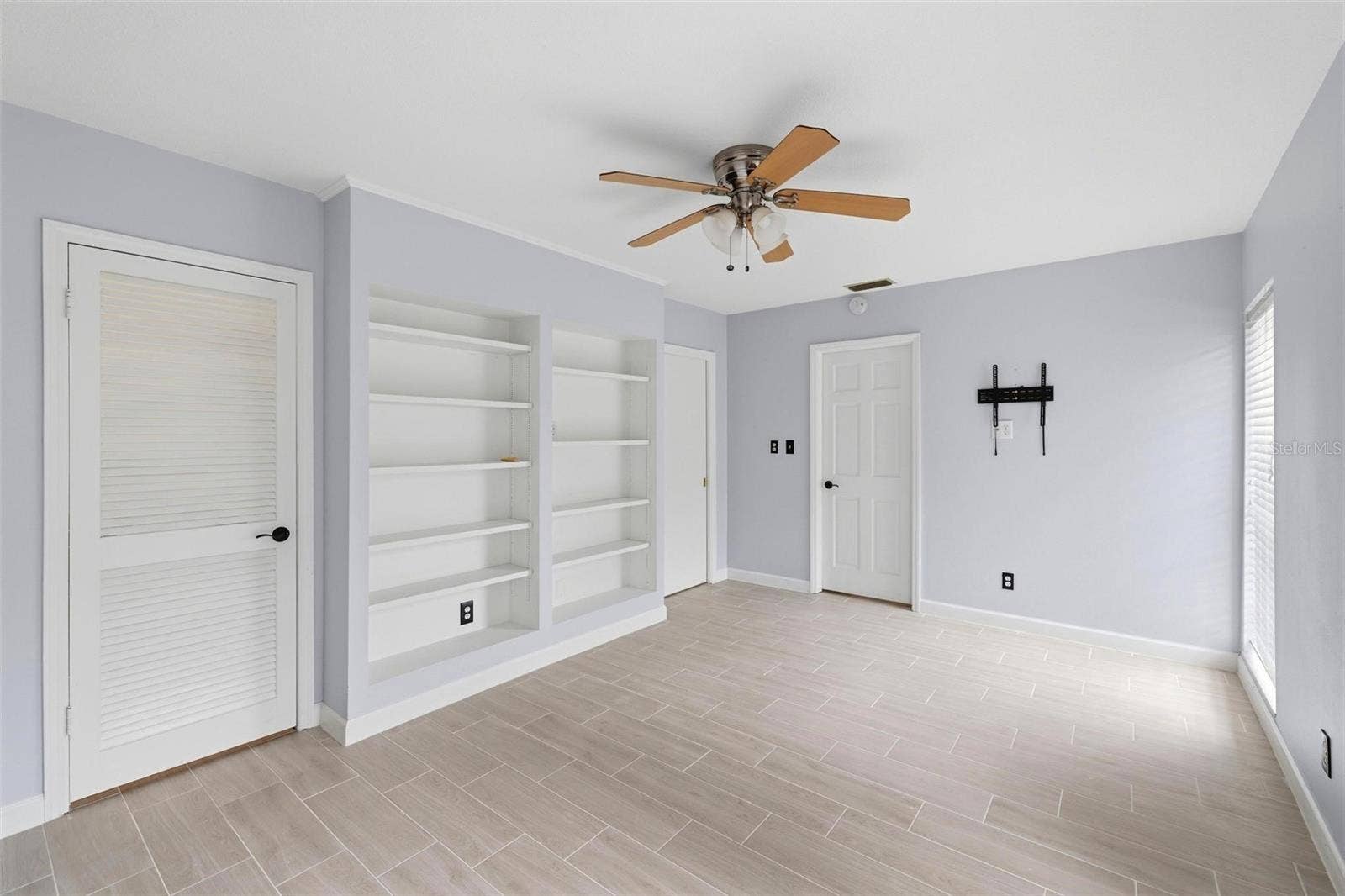 Full view of the built in shelves in the 2nd bedroom.  Door to closet and door to laundry room.