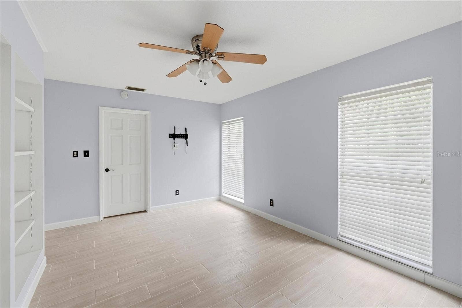 2nd bedroom bright and cheerful with two long, large windows full of natural light.  Built shelving unit.