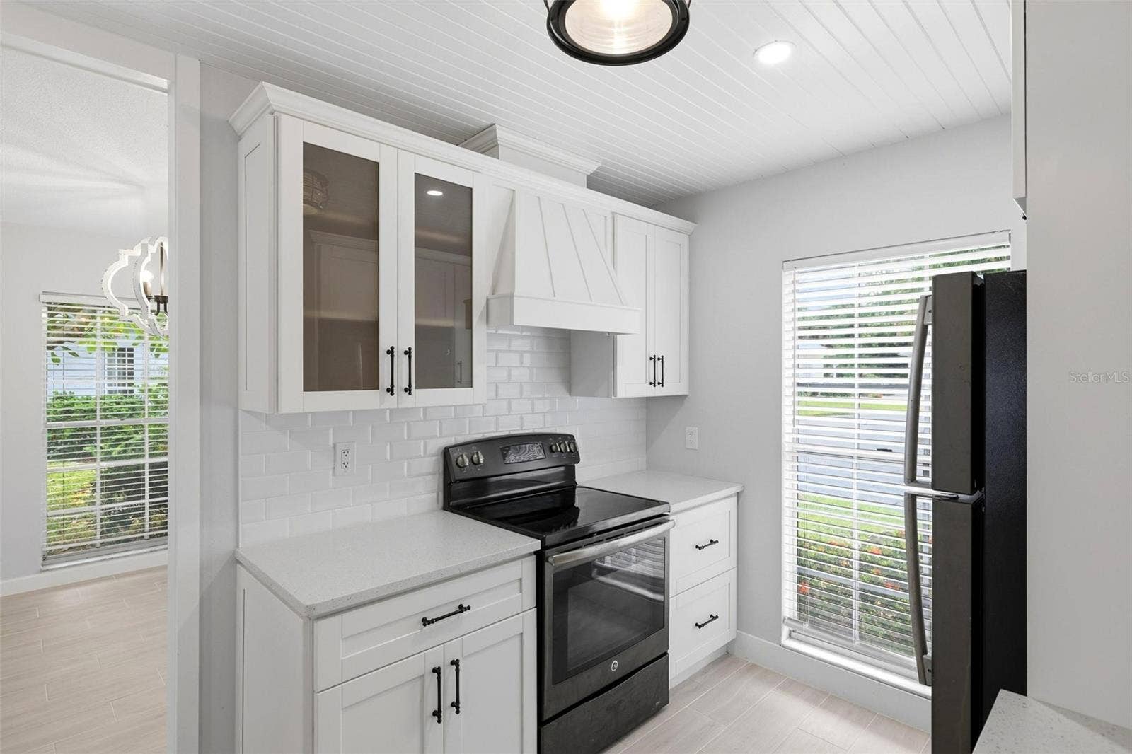 Another view of the kitchen including the stove and cabinetry.  Glass door cabinet for your glassware or special dishes.