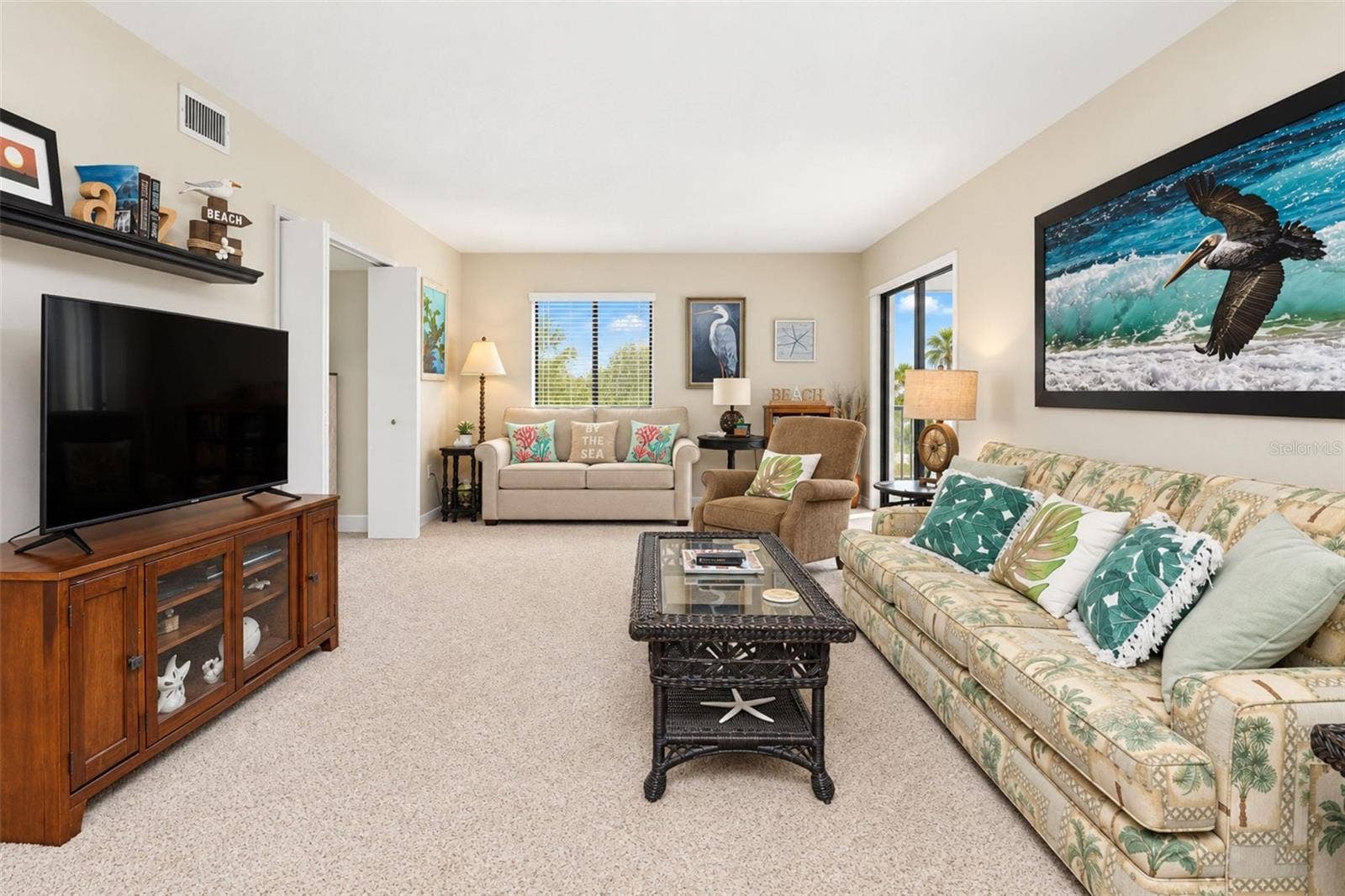 2950 N BEACH ROAD, #A321, Englewood, FL 34223 The living room has carpeted flooring and sliding glass doors to the lanai.