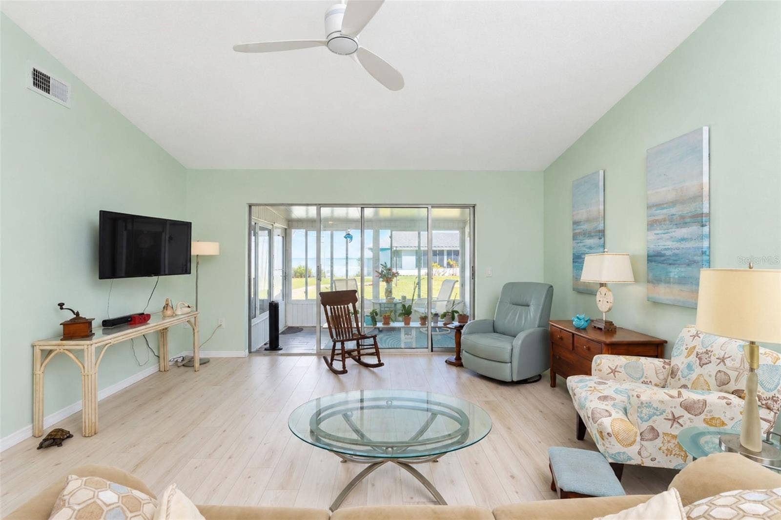 6468 HAMLET DRIVE, #B, Englewood, FL 34224 The living room has stylish wood laminate flooring, a ceiling fan and sliding glass doors to the Glass-Enclosed Florida room.